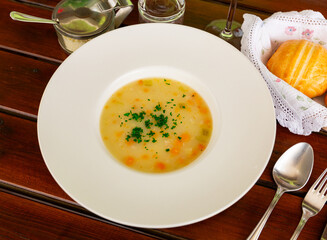 Barley and vegetable thick healthy soup served in white plate on table