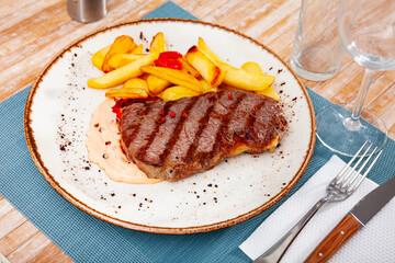 Juicy cooked beef steak on a plate with potatoes.