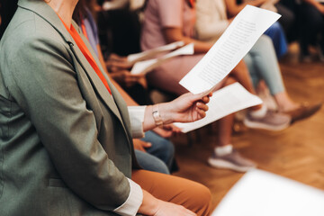 Choir rehearsal, vocal class singing in the auditorium hall, group of students on stage holding white sheets and singing, orchestra vocals class in music school with a teacher, adults sing in chorus