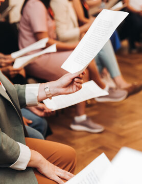Choir rehearsal, vocal class singing in the auditorium hall, group of students on stage holding white sheets and singing, orchestra vocals class in music school with a teacher, adults sing in chorus