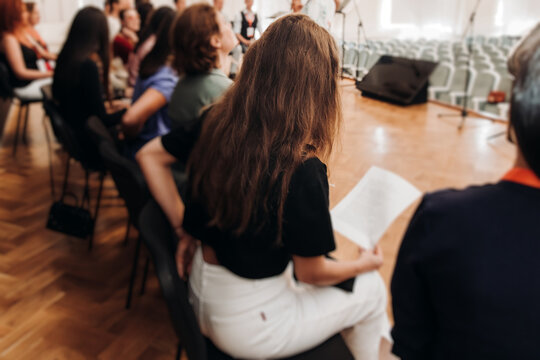 Choir rehearsal, vocal class singing in the auditorium hall, group of students on stage holding white sheets and singing, orchestra vocals class in music school with a teacher, adults sing in chorus