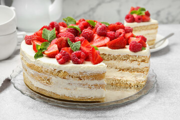Tasty sponge cake with fresh berries and mint on light gray table, closeup