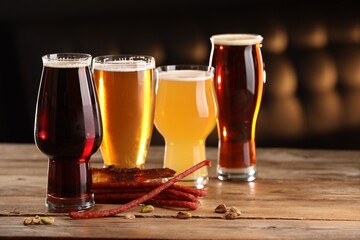 Glasses with different types of beer and snacks on wooden table indoors