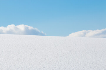 Fluffy white clouds and blue sky over snow field winter landscape background