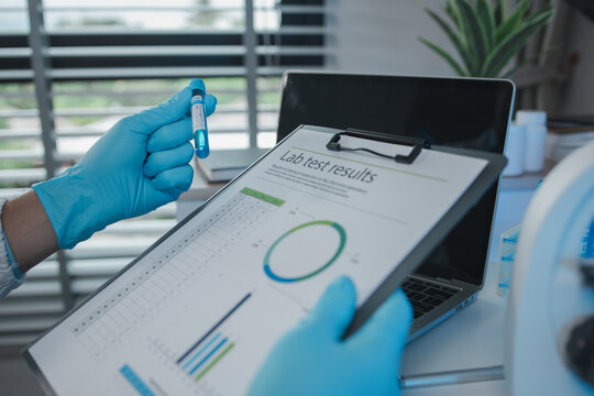 A scientist is reviewing lab results and documents receives from researchers involved in chemical testing, chemist is concentrating on reading test results document