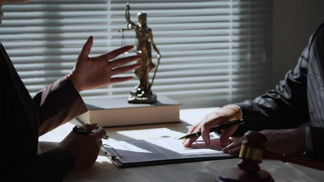 Lawyers in suits discussing the terms of a contract or agreement, negotiating points and eventually signing a document in an office