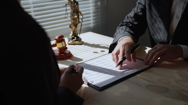 Lawyer pointing at key details while explaining contract terms to a client before signing. Important discussions occur in a professional office setting, ensuring clarity and understanding