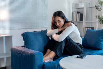 Young businesswoman feeling sad and depressed while sitting on sofa at home