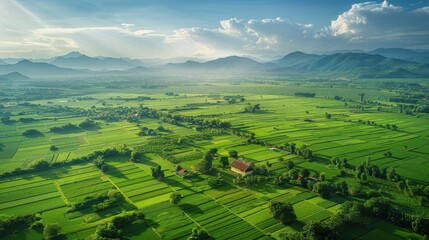 Obraz premium A breathtaking aerial view of lush green fields and mountains under a clear blue sky, showcasing the beauty of rural landscapes.