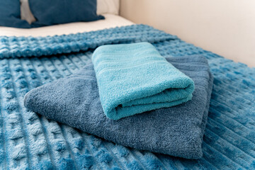 On the bed, there are two soft and inviting blue towels elegantly stacked one on top of the other,...
