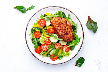 Tasty salad with grilled duck breast with vegetables and lettuce on white background, top view