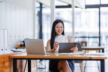 Business asian woman or female worker using a laptop computer to analyse her financial data.business people research or financial strategy in company concept. Laptop white screen mockup.