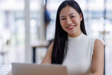 Business asian woman or female worker using a laptop computer to analyse her financial data.business people research or financial strategy in company concept. Laptop white screen mockup.