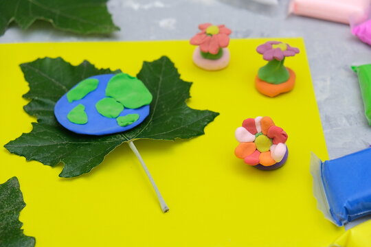 Child sculpturing plasticine planet for earth day. Protection of environment, Save our planet. Ecology concept. Concept of art learning and education