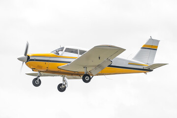 Yellow and white general aviation aircraft in flight. Single engine propellor driven piston airplane on departure. Low wings and fixed landing gear