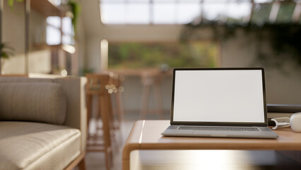 A laptop on a modern hardwood coffee table in a contemporary coffee shop seating area.