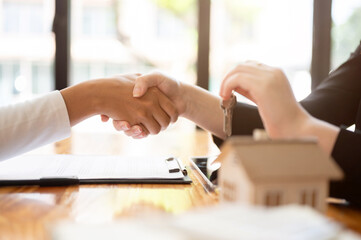 A real estate agent having a meeting with a client in the office to sign a contract, shaking hand.