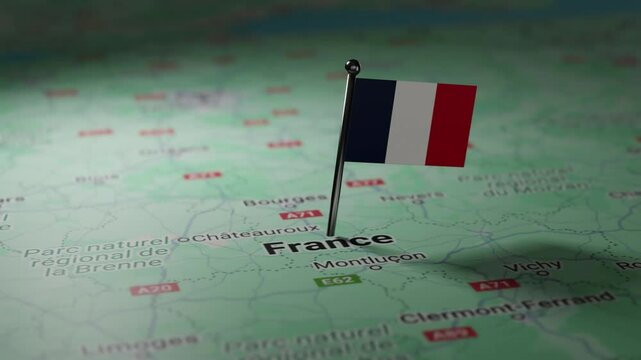 A small French flag is pinned on a map of France.
