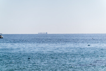 Calm blue sea with the silhouette of a large ship on the horizon