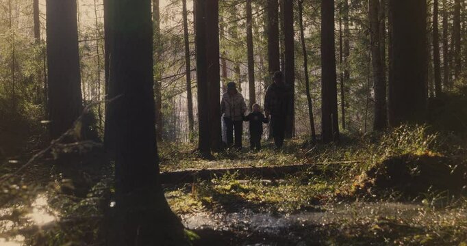 Happy grandparents and child walking in nature forest on first day of spring in Finland