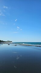 Beach shore with sky and clouds reflection on the sand