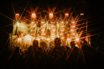 A lively night concert featuring vibrant green and yellow stage lights, casting starburst effects...