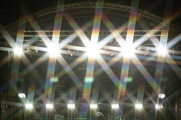 A powerful display of bright stage lights creates a vibrant starburst pattern in front of a concert...