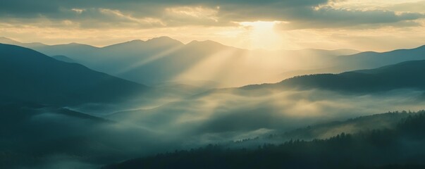 Sunrise over misty mountain range with sun rays, serene landscape