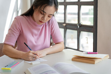 Asian girl student doing exam hand holding pencil writing answer in university classroom education high school or university student taking notes while preparing for exam