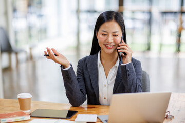 Business Asian woman freelancer is working her job on a laptop computer and phone call in the office. Doing accounting analysis report real estate investment data, Financial and tax systems concept.	