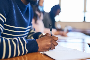 Hands, writing and notes in classroom at university for problem solving, student or assessment at...