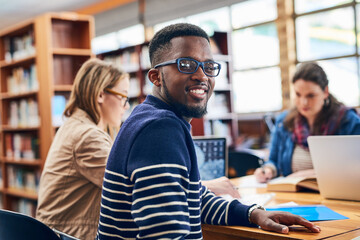 Man, student and portrait in library with group, learning and notes at campus, excited and diversity at college. Person, education and development with pride for scholarship, study or smile in Canada