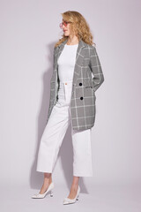 Fashion female model in grey checked coat, white culottes jeans, top, heels shoes, and sunglasses.