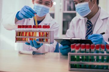 Two male researchers are conducting chemical research in a science lab, carefully analyzing...