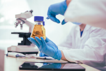 Two male researchers are conducting chemical research in a science lab, carefully analyzing substances at a desk filled with scientific instruments and chemical solutions in a well-organized
