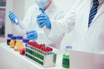 Two male researchers are conducting chemical research in a science lab, carefully analyzing substances at a desk filled with scientific instruments and chemical solutions in a well-organized