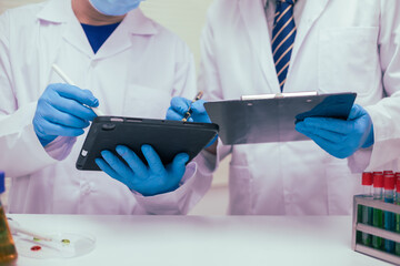 Two male researchers are conducting chemical research in a science lab, carefully analyzing...