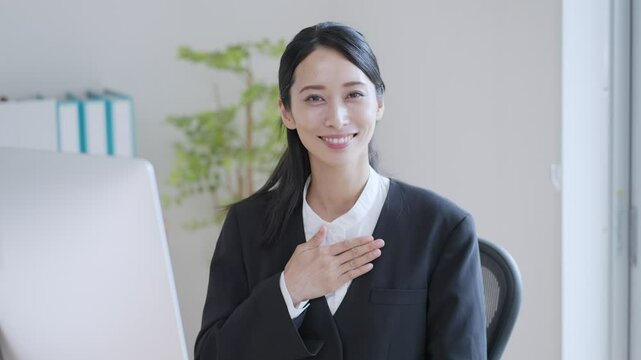胸に手を当てるビジネスウーマン