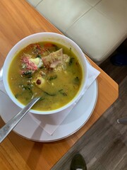 Red Snapper fish spicy soup Sour curry in a white bowl with garlic, tomatoes, vegetable and chili turmeric sauce and various spices, over wooden table. delicious food.