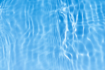 Blue water with ripples on the surface. Defocus blurred transparent blue colored clear calm water surface texture with splashes and bubbles. Water waves with shining pattern texture background.