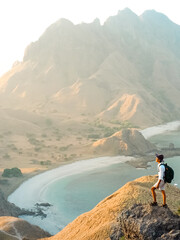 Happy man standing and looking on the rock at Padar island in Komodo National Park, Indonesia....