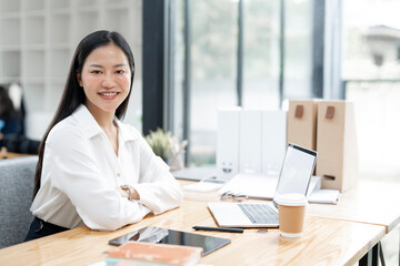 Young happy successful business woman working with laptop in corporate office