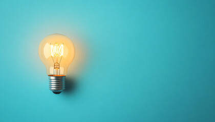 A glowing light bulb mounted on a turquoise wall, symbolizing brightness and creativity in modern design.