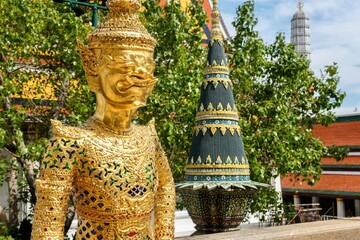 Asurapaksi, a gold giant-and-bird chimera statue beside a panom mak (banana leaf offering) sculpture at the Temple of the Emerald Buddha (Wat Phra Kaew) inside the Grand Palace - Bangkok, Thailand 