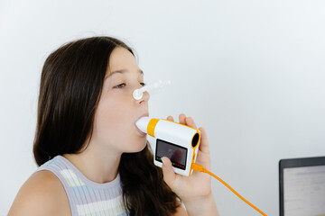Girl testing breathing function by spirometry in doctors office. Diagnosis of respiratory function...