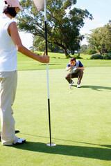 Obraz premium Hole, coaching and couple on golf course for game, outdoor fun and fitness on weekend morning together. Help, woman and man on green grass for outdoor sports, challenge and competition with exercise.
