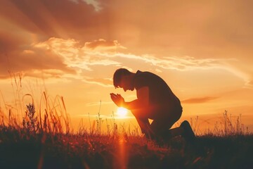 Christian prayer. Man on his knees praying on sunset background. Kneeling prayer to God. Worship and praise