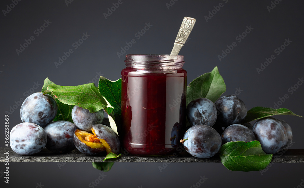 Wall mural plum jam and fresh berries on a black background.