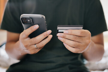 A man holding smartphone and credit card for online electronic transaction payment