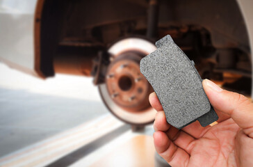 Car brake system maintenance concept , mechanic hand holding a car brake pad with braking system of...